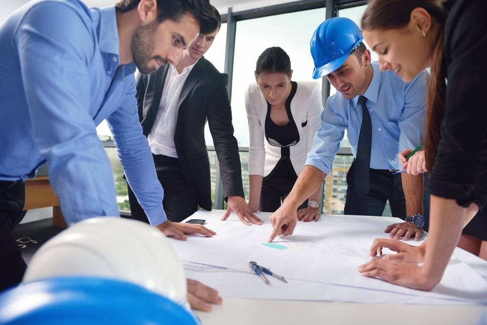 business people group on meeting and presentation in bright modern office with construction engineer architect and worker looking building model and blueprint planbleprint plans business people group on meeting and presentation in bright modern office with construction engineer architect and worker looking building model and blueprint planbleprint plans